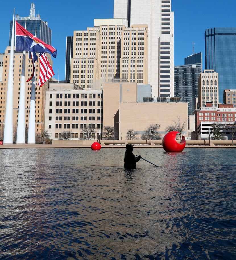 City of Dallas employee Kenneth Argusta cleans the reflecting pool at Dallas City Hall in...