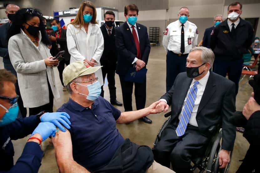 Texas Governor Greg Abbott (right) holds the hand of 86 yr-old Al Godfrey of Arlington as he...