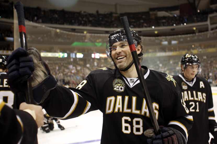 Dallas Stars Jaromir Jagr laughs with an equipment manager as he receives a new stick during...