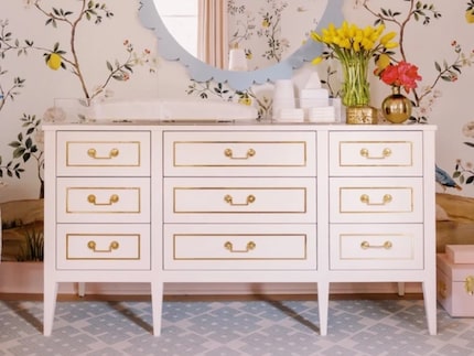 White dresser with gold detailing, with a blue mirror and floral wall covering