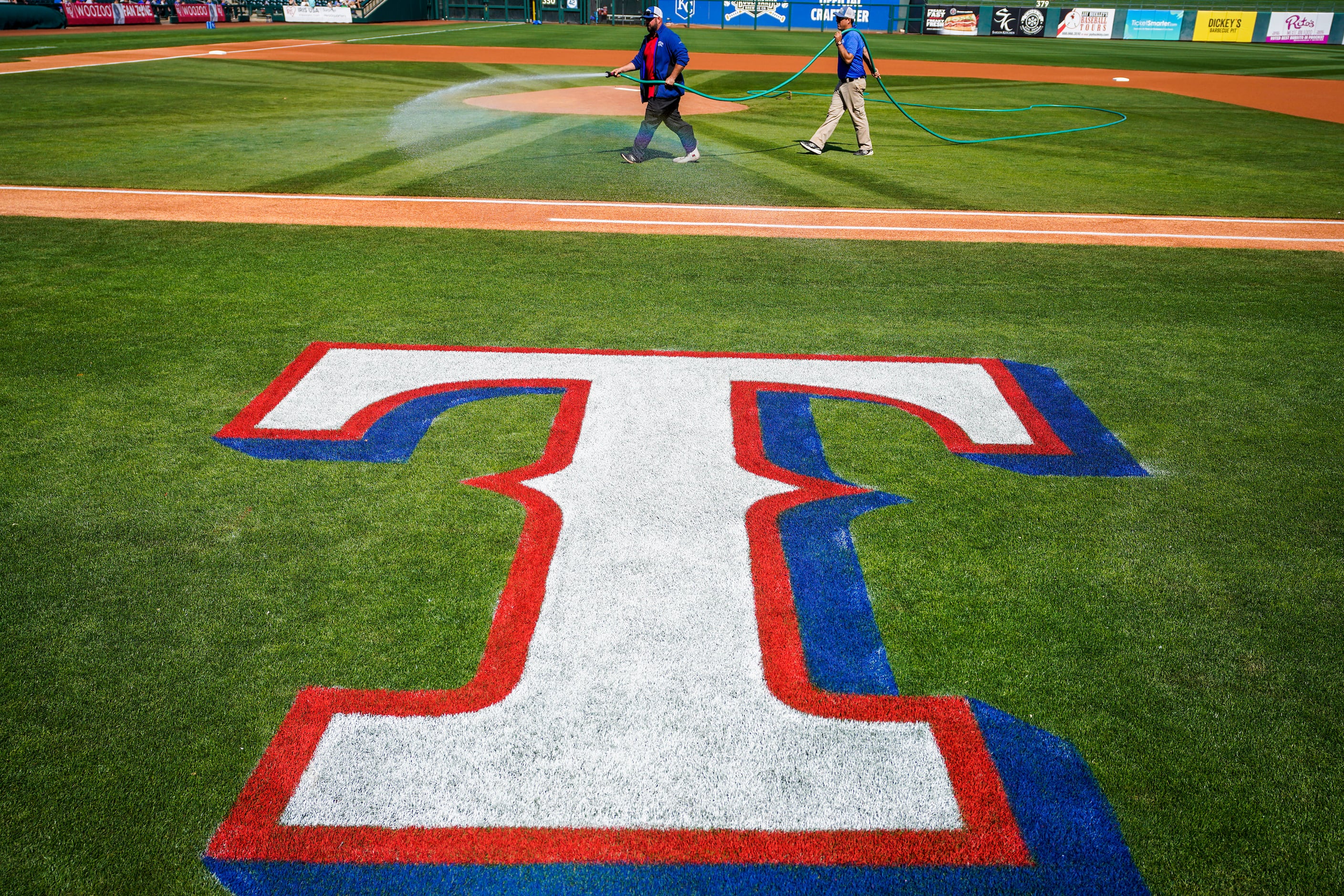 Groundskeepers prepare the field before a spring game between the Texas Rangers and the...