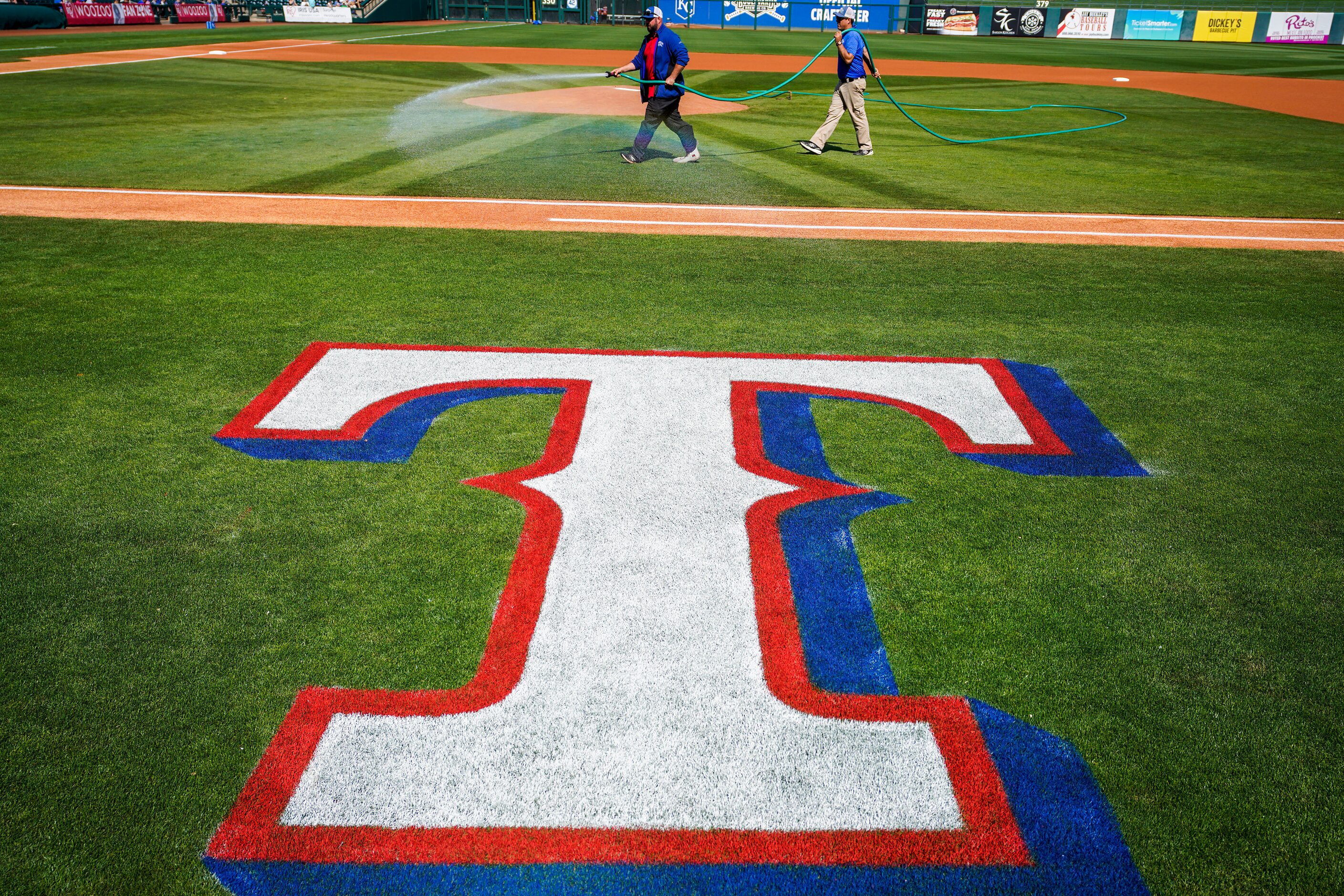 Groundskeepers prepare the field before a spring game between the Texas Rangers and the...