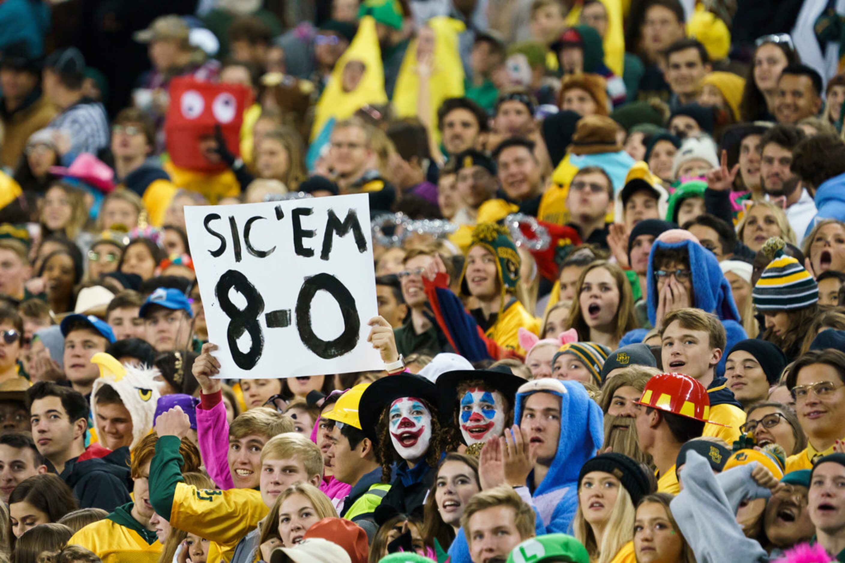 Baylor fans wear Halloween costumes in the stands as they cheer their team during the first...