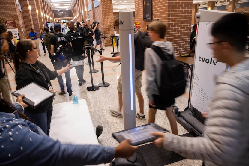 Students hand their laptops to the side before walking through the Evolv Express weapons...