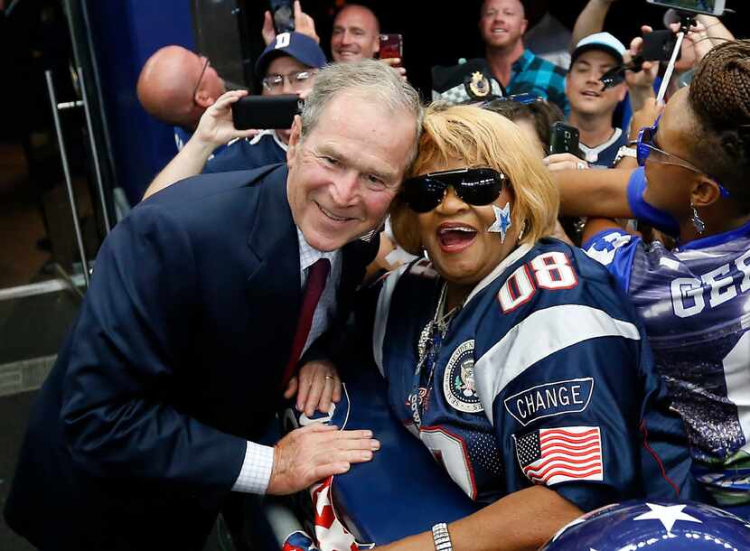 Former President George W. Bush (left) poses for a photograph with a Dallas Cowboys fan...