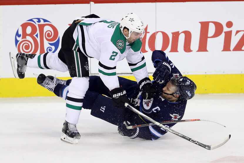 Dallas Stars' Dan Hamhuis (2) hits Winnipeg Jets' Blake Wheeler (26) to the ice during the...