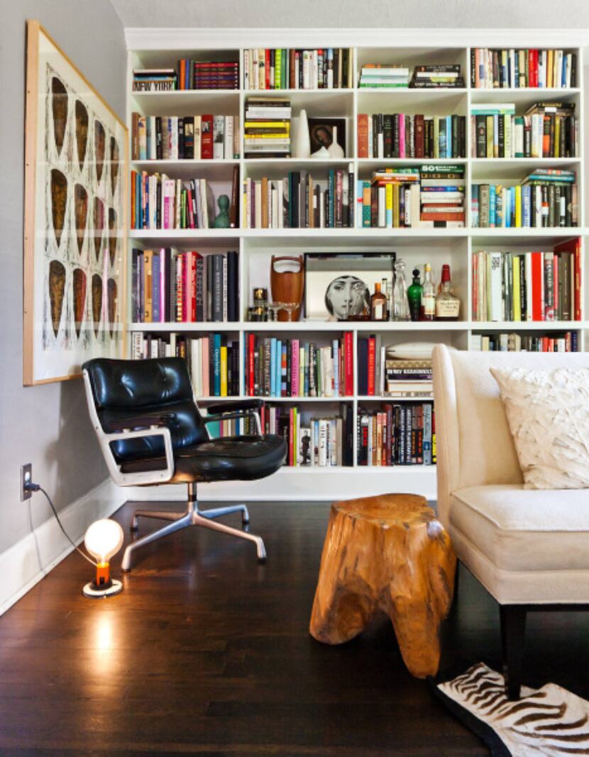 The living room’s custom shelves hold books and a built-in bar. The Eames executive chair is...