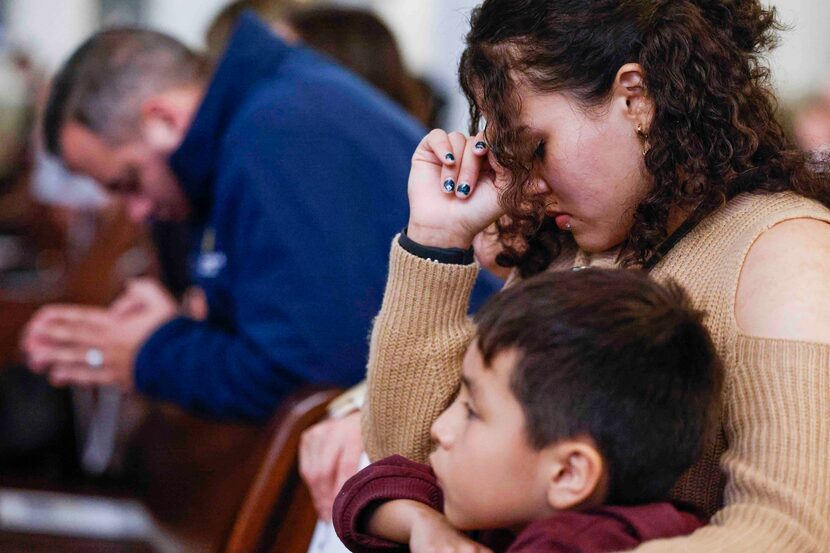 Giselle Huerta sitting by her son Abdel Monasterio, 7, kneels as she prays during a memorial...