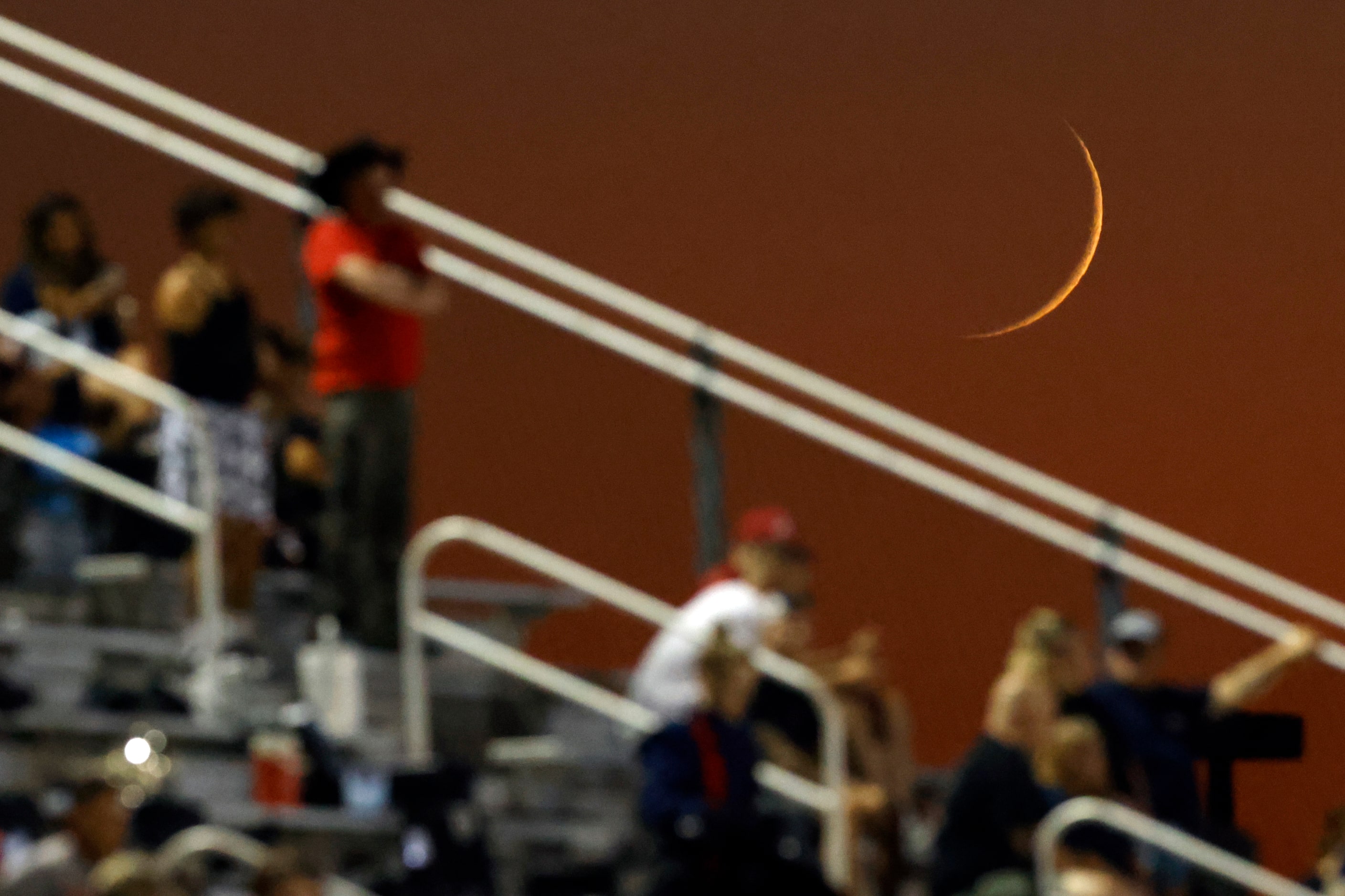 The moon sets behind Denton Ryan fans during the first half of a District 3-5A game against...