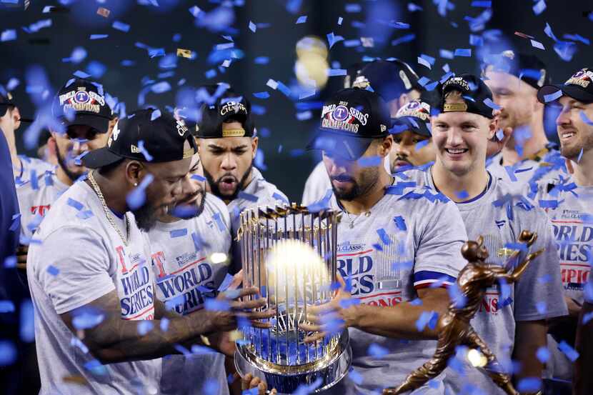 With confetti raining down, Texas Rangers outfielder Adolis Garcia (left) checks out the...
