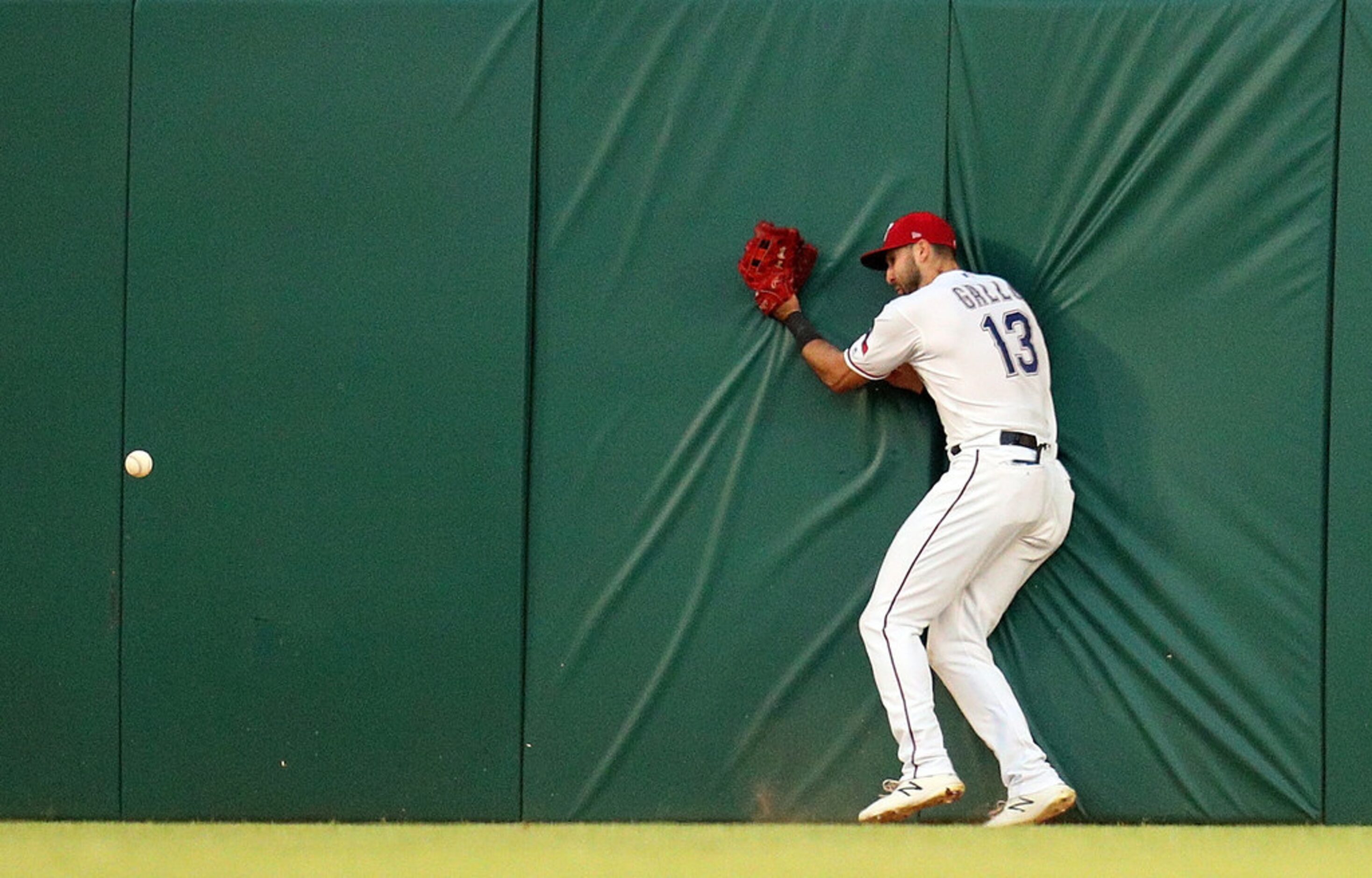 ARLINGTON, TEXAS - MAY 31: Joey Gallo #13 of the Texas Rangers hits the wall trying to field...