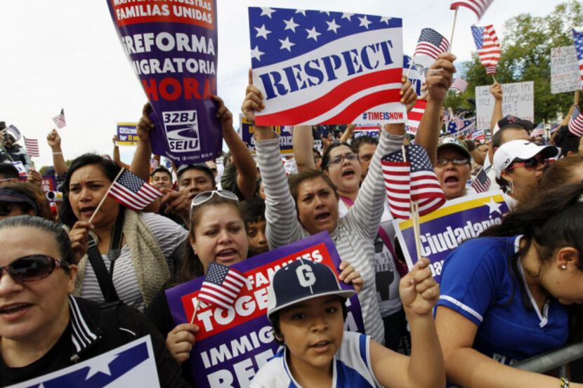 Demonstrators hold up their banners as the shout during a immigration a rally on the...