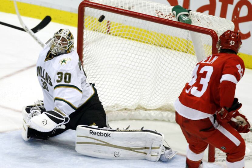Stars goalie Andrew Raycroft (30) is unable to stop a shot by Detroit's Darren Helm (right)...