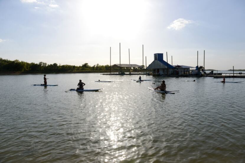 Local residents try out paddleboard yoga on Lewisville Lake. Paddleboard yoga came to...