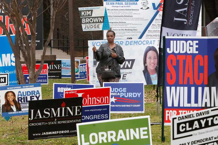 Cheryl Miller holds a “Kim Brown for Judge" sign as she stands with other candidates signs...