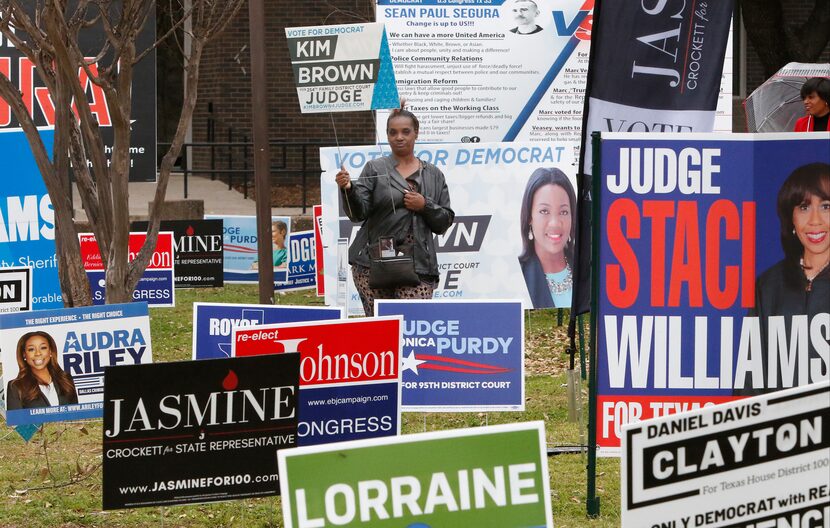 Cheryl Miller holds a “Kim Brown for Judge" sign as she stands with other candidates signs...