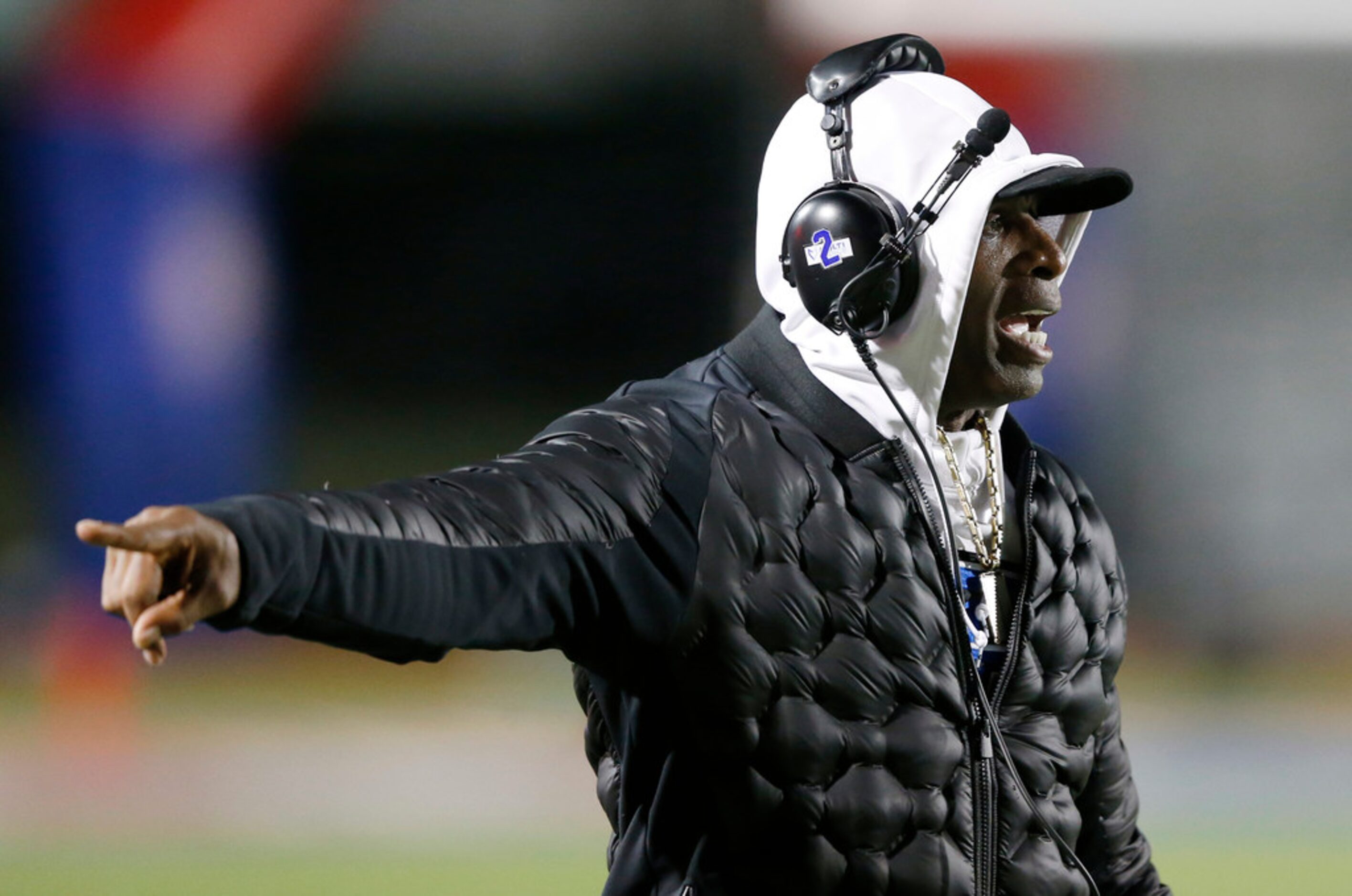 Trinity Christian's offensive coordinator Deion Sanders communicates to the players in a...