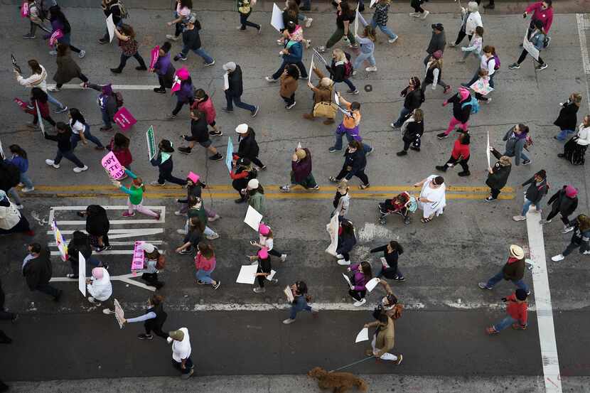 Participants in the 2020 Dallas Women's March walk along Harwood Street on their way to a...