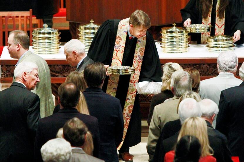 The Rev. Paul Rasmussen   passes communion to parishioners during Sunday worship at Highland...
