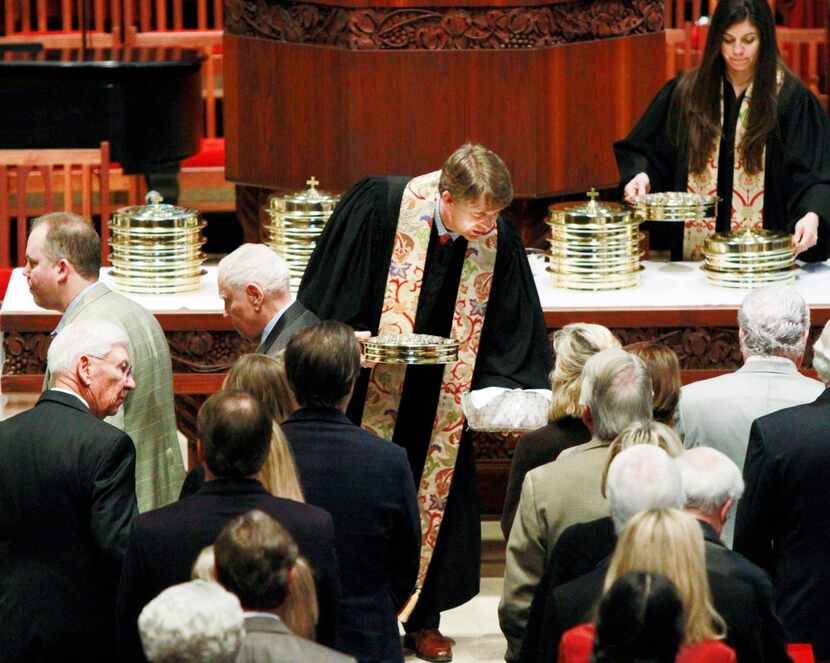 The Rev. Paul Rasmussen   passes communion to parishioners during Sunday worship at Highland...