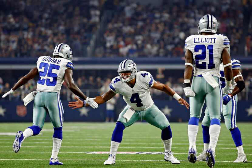 Dallas Cowboys quarterback Dak Prescott (4) high fives running back Lance Dunbar after his...