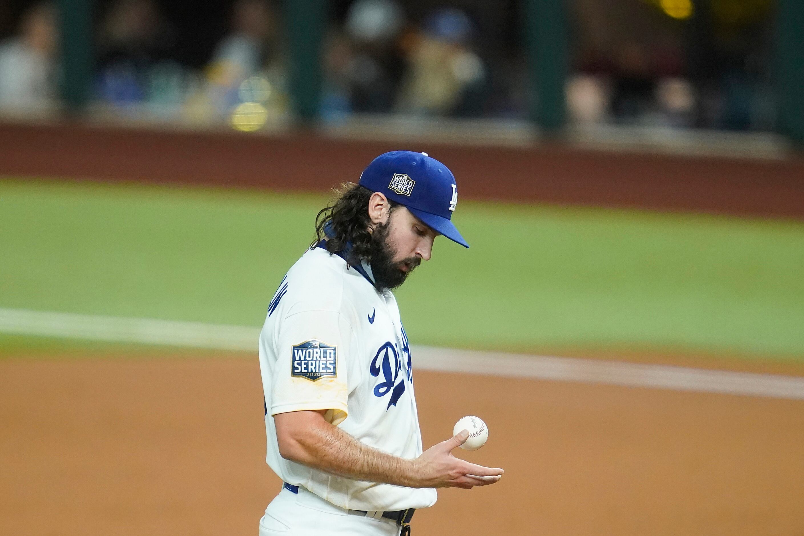 Los Angeles Dodgers starting pitcher Tony Gonsolin looks at the ball after giving up a walk...