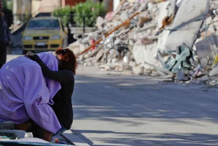 Un hombre y una mujer se ofrecen consuelo frente a un edificio derribado por el sismo en...