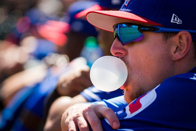 Texas Rangers outfielder Carlos Tocci blows bubbles in the dugout before a spring training...