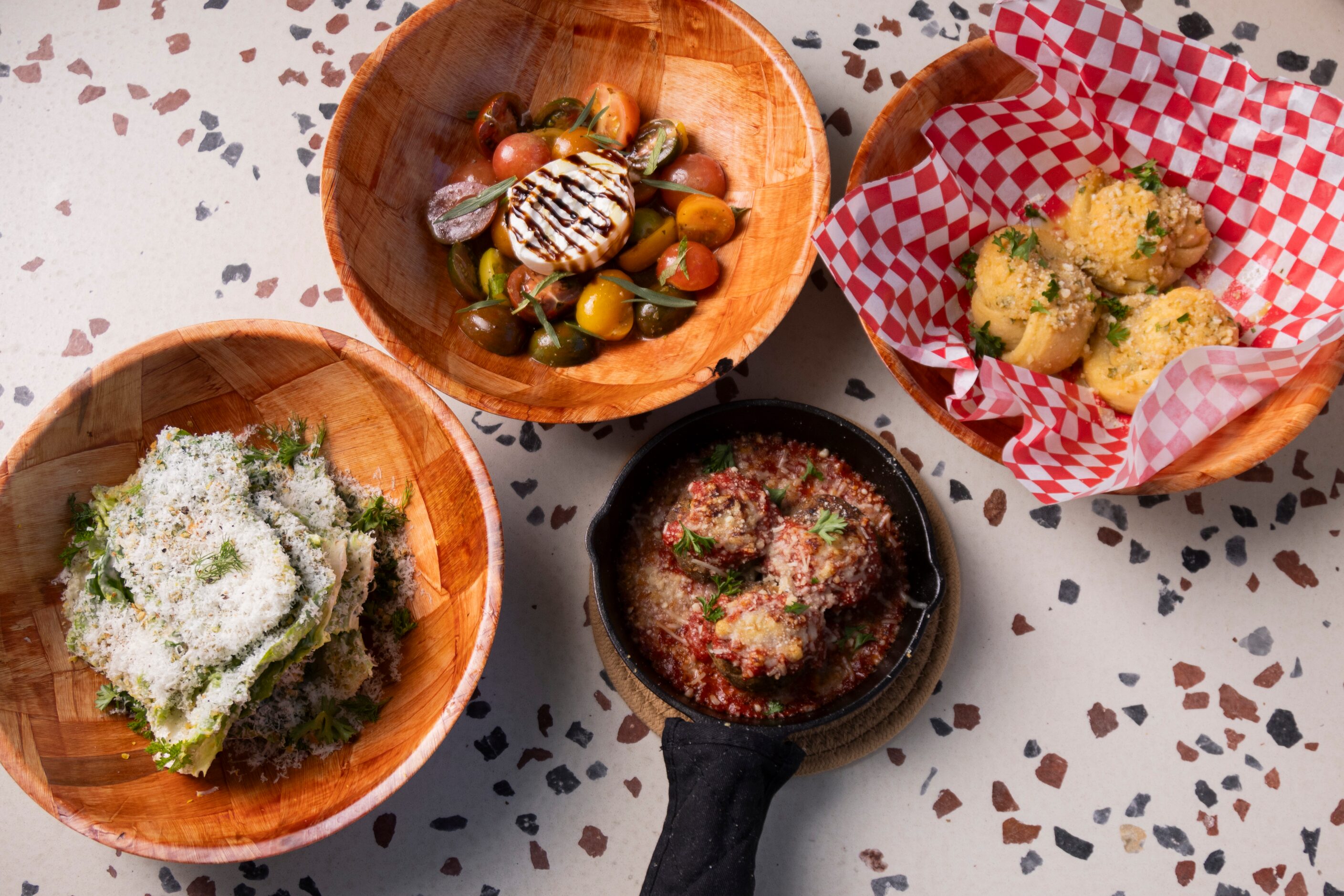 (From left) Caesar Salad, Tomato Burrata Salad, Meatball App and Garlic Knot served at the...