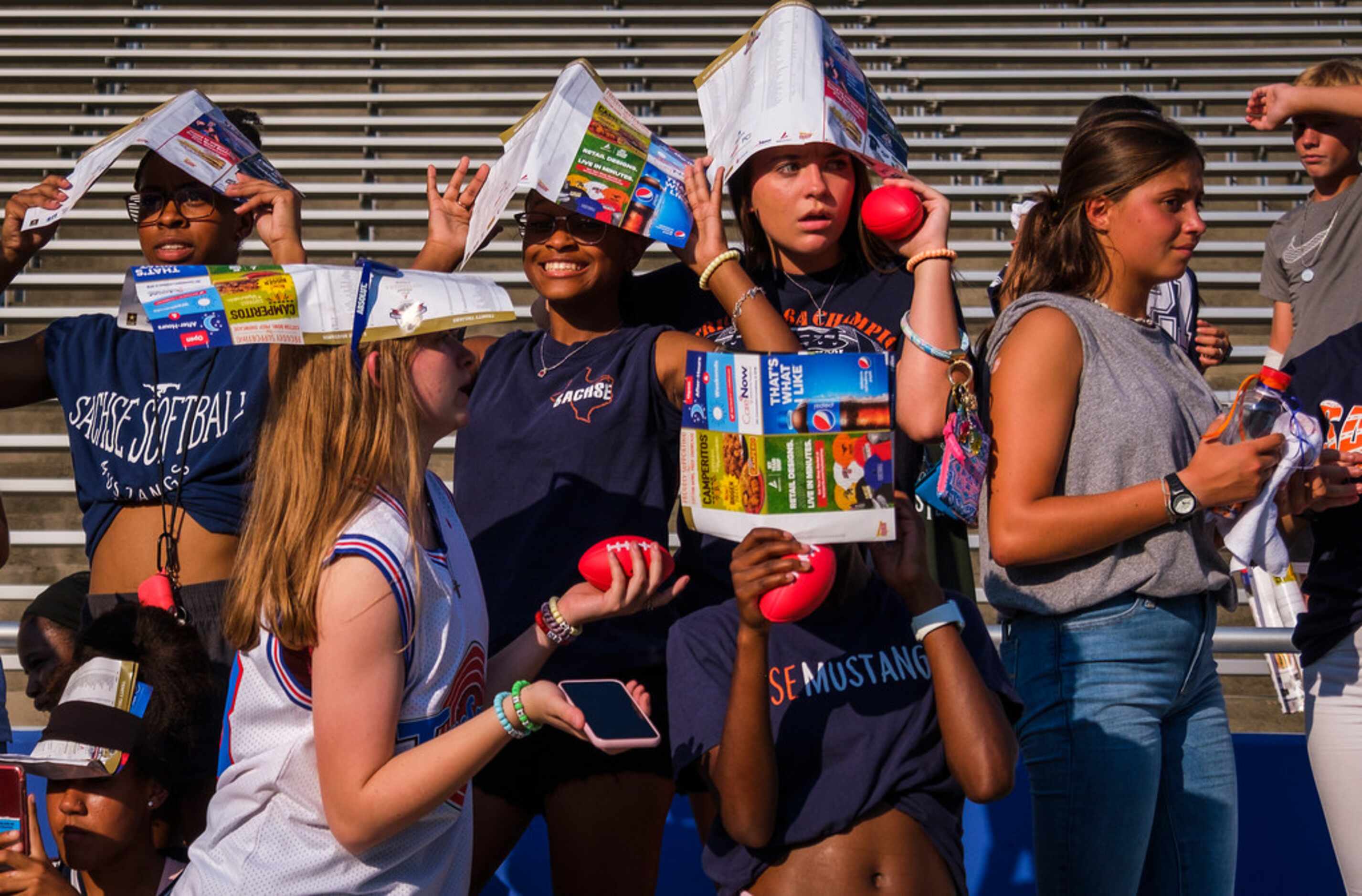 Sachse fans use programs to shield themselves from the sun during the first half of a high...