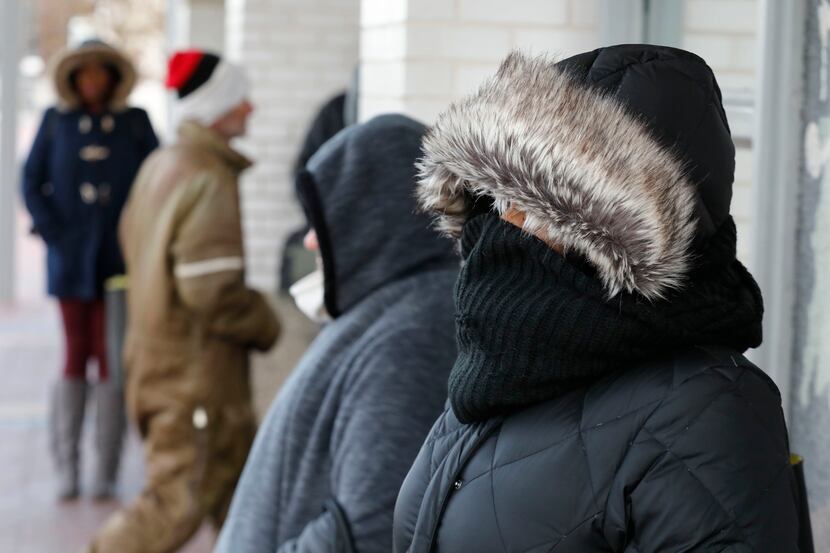 Denise Jenkins, right, of Grand Prairie braves the cold frigid weather with other commuters...