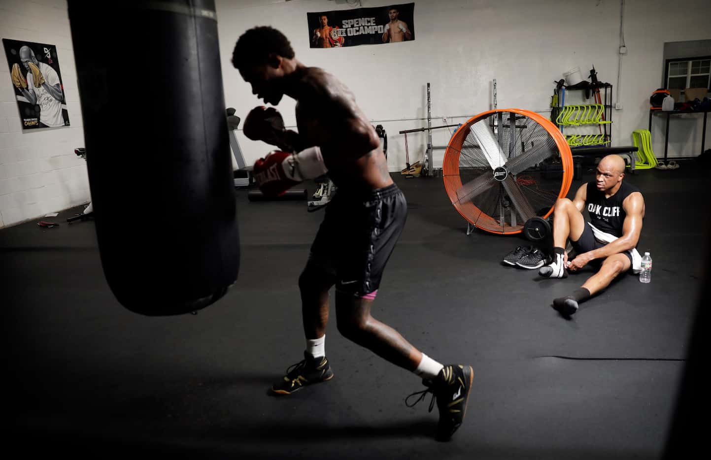 Trainer Derrick James (right) watches as professional boxer Errol Spence Jr. works the bag...