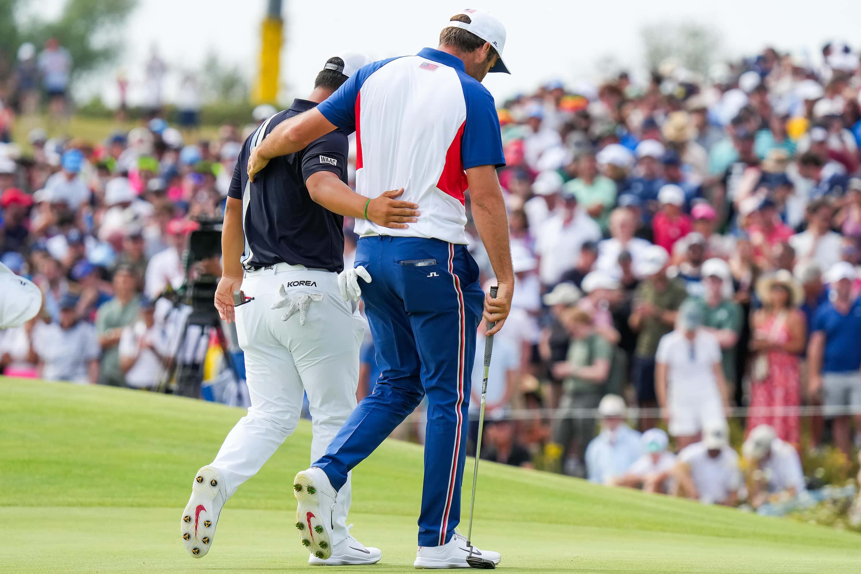 Scottie Scheffler of the United States (right) walks arm-in-arm with Tom Kim of South Korea...