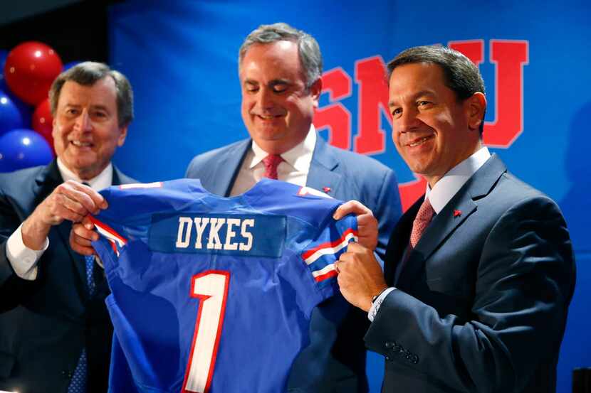 SMU president Gerald Turner (left) and athletic director Rick Hart (right) hand new SMU...