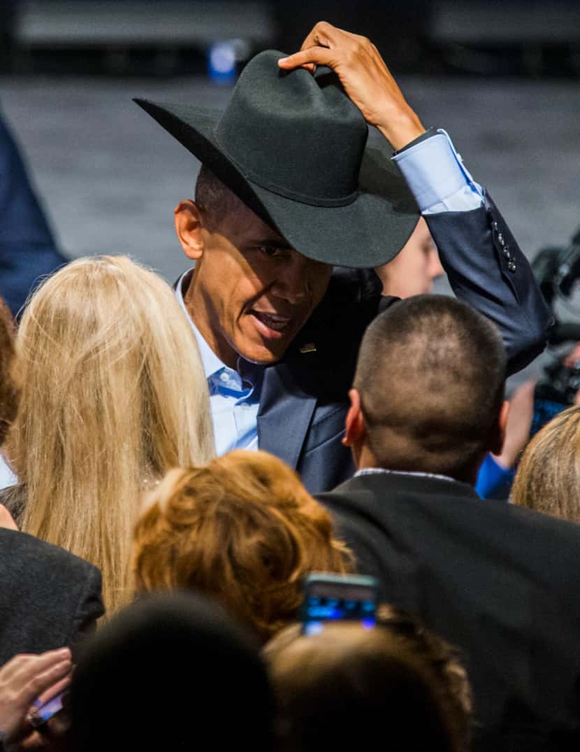 President Barack Obama tries on a cowboy hat from a member of the crowd after speaking at a...