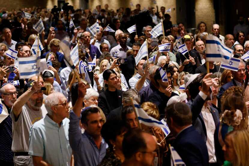 Attendees hold Israeli flags during a community solidarity gathering for Israel at Temple...