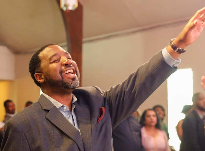 Pastor Andre Byrd Sr. of New Covenant Christian Fellowship Church raises his hand in praise...