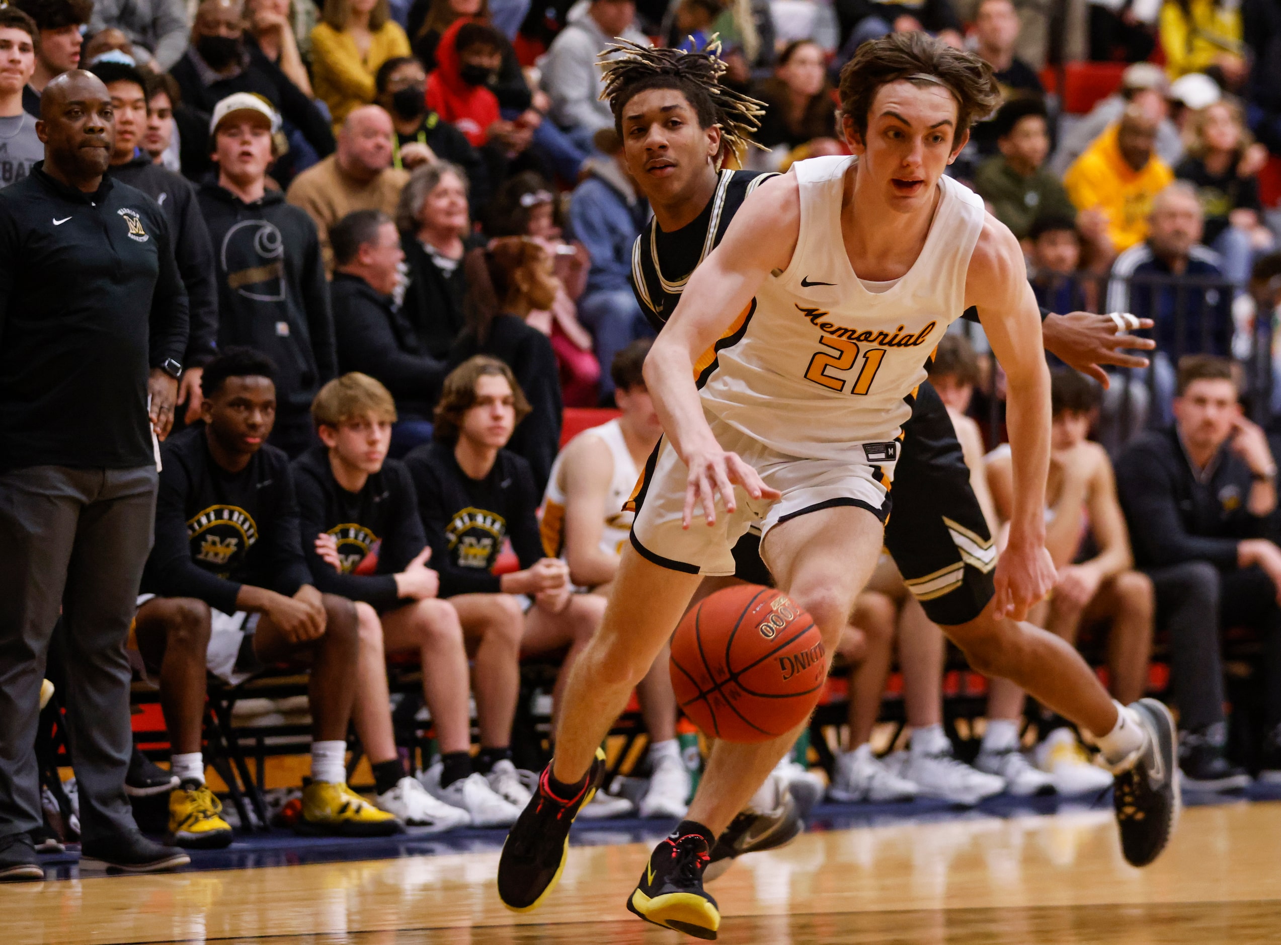 Memorial High School Drew Steffe (21) dribbles the ball up the court after passing The...