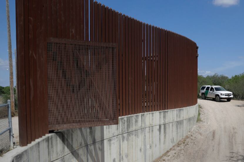 A U.S. Customs and Border Patrol agent passes along a section of border levee wall in Hidalgo.