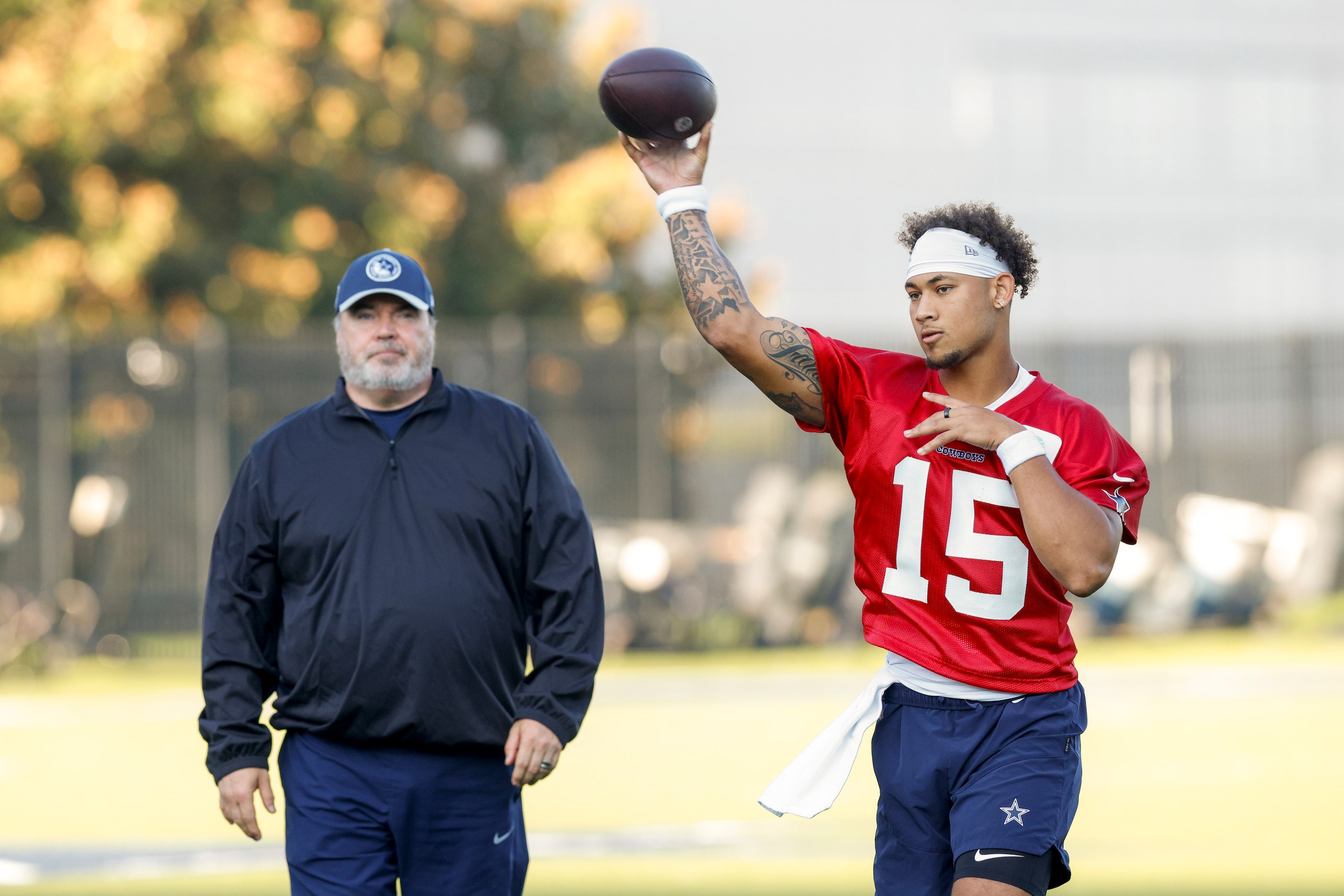 Dallas Cowboys head coach Mike McCarthy watches as quarterback Trey Lance (15) throws a pass...