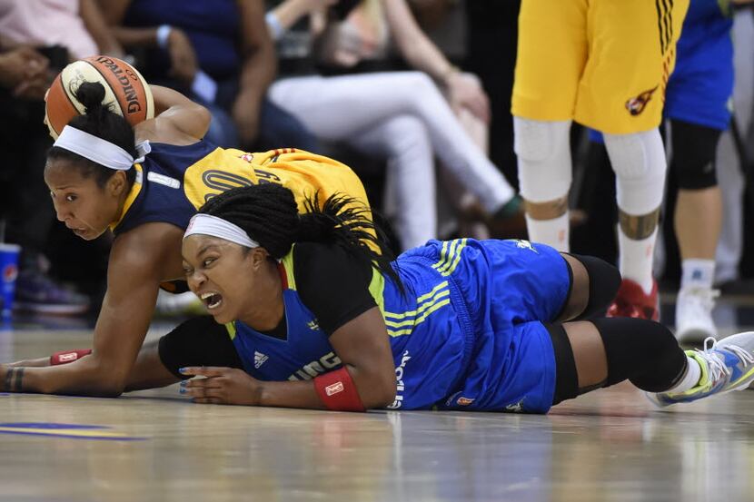 Indiana Fever guard Briann January, left, and Dallas Wings guard Odyssey Sims fight for a...