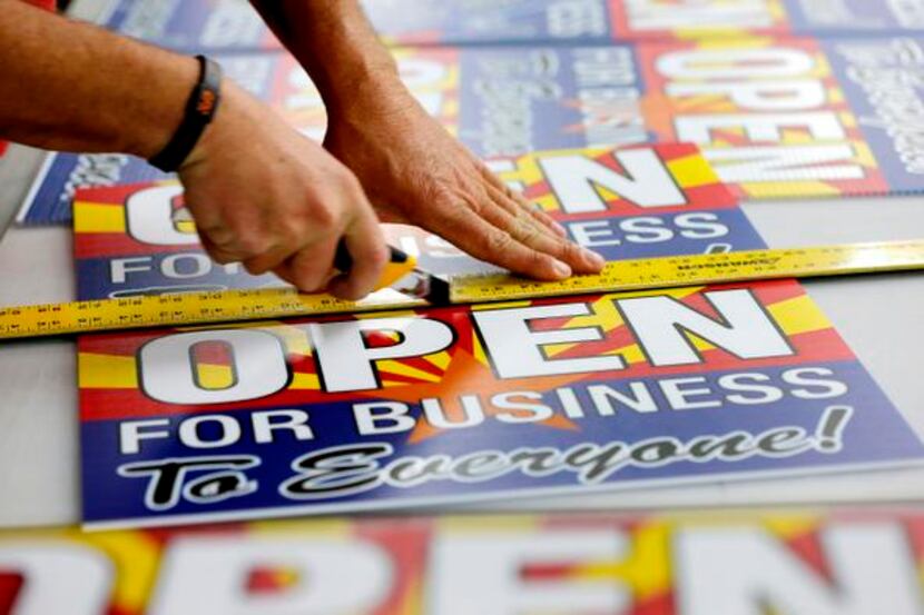 
Signs reading “Open to business for everyone” were produced at Fast Signs in Phoenix to...
