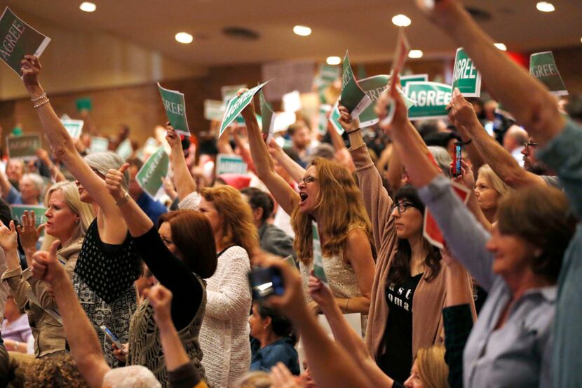 People show their "agree," signs during a town hall meeting with Rep. Pete Sessions,...