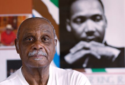 Rev. Peter Johnson of Dallas in front of a poster of Dr. Martin Luther King Jr. in his Oak...