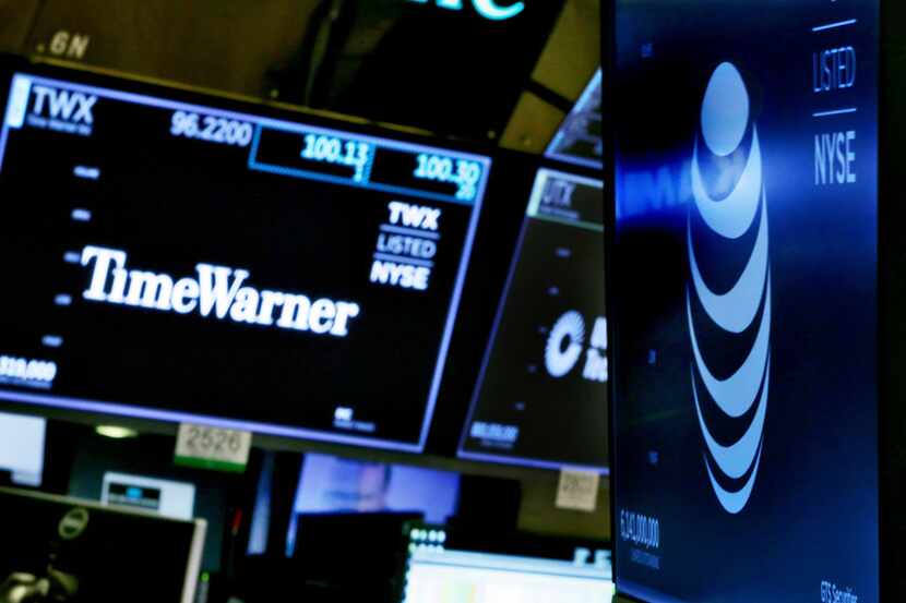 FILE - In this June 13, 2018, file photo, the logos for Time Warner and AT&T appear above...