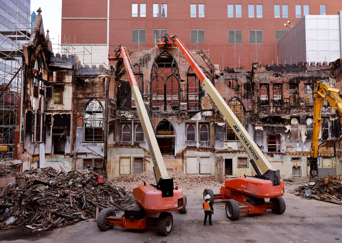 Demolition crews remove parts of the three point arch at the top of a crumbling north wall,...