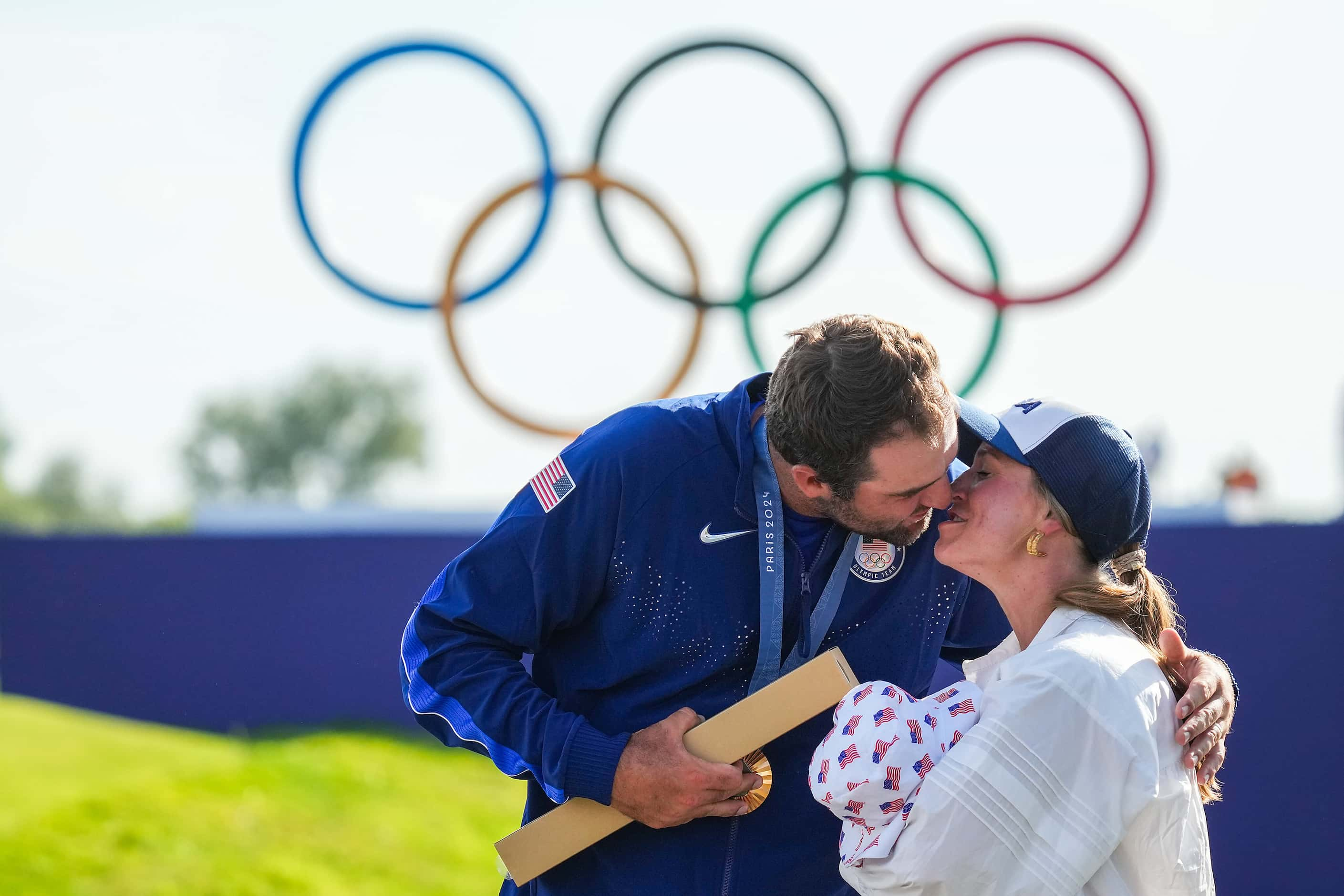 Gold medalist Scottie Scheffler of the United States kisses his wife Meredith who holds...