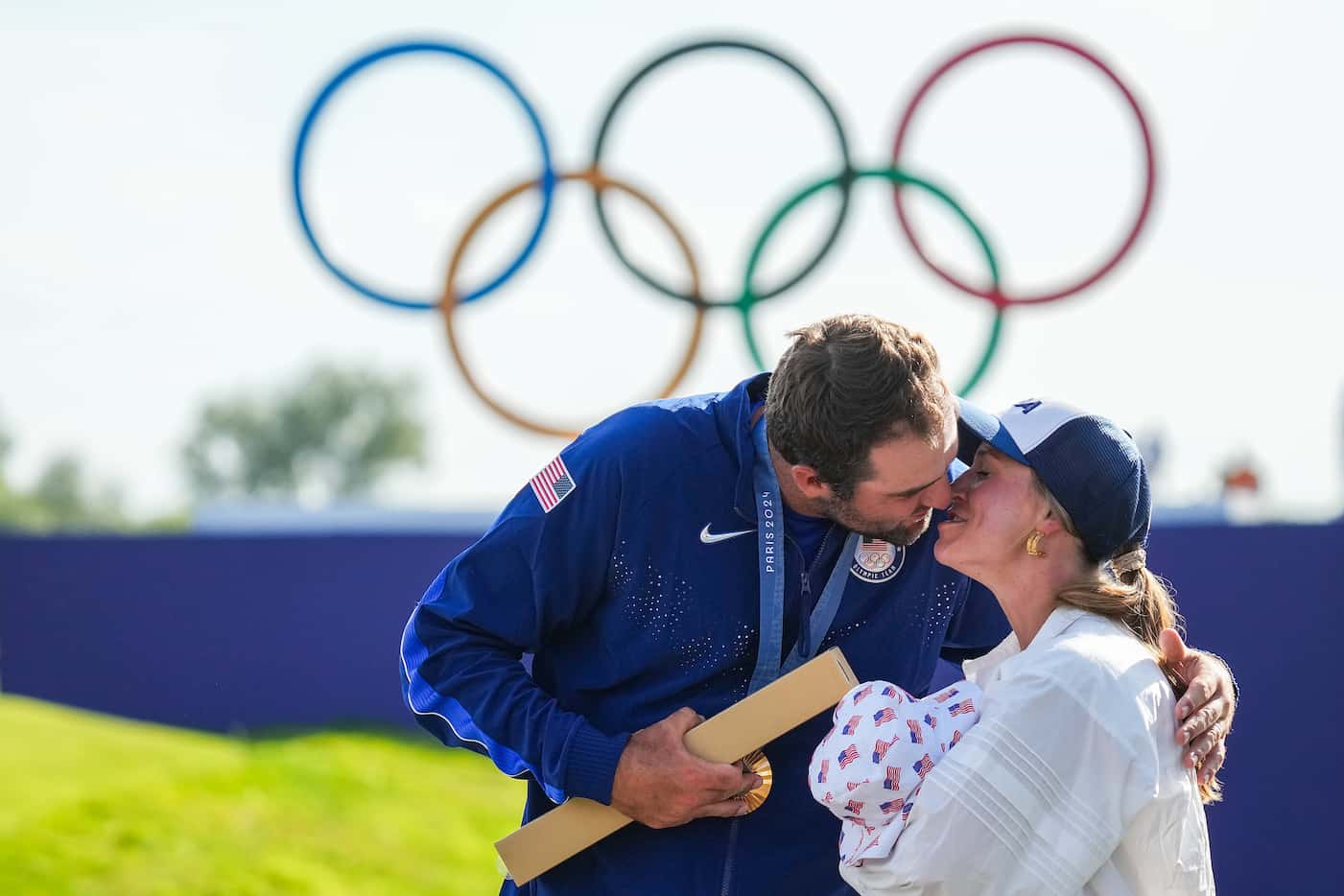 Gold medalist Scottie Scheffler of the United States kisses his wife Meredith who holds...