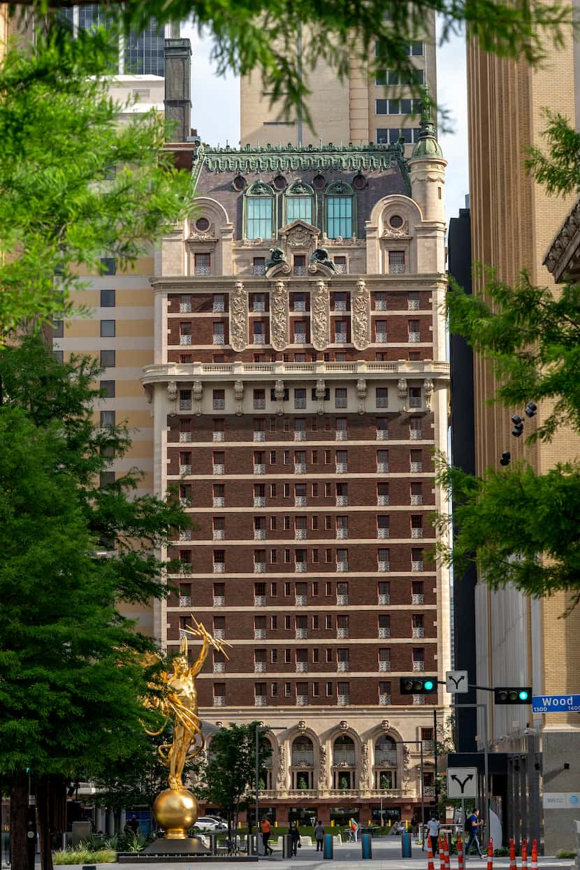 The Adolphus Hotel is seen through trees from the AT&T Discovery District. 