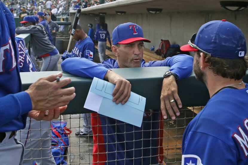 Texas bench coach Tim Bogar, center, talks with first baseman Mitch Moreland in the dugout...